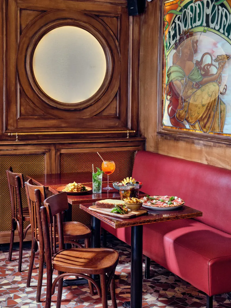 La salle de la brasserie Batistou : boiseries, banquettes bordeaux et affiches anciennes