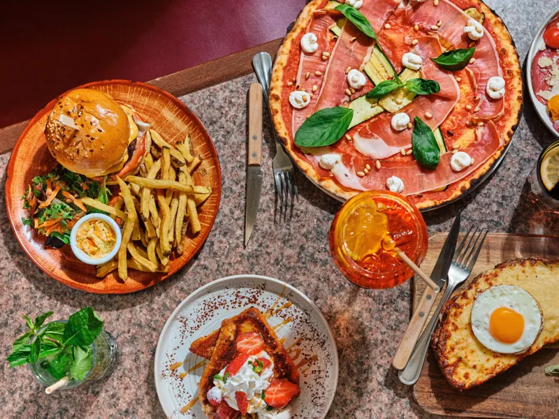 Burger, pizza romaine et plats de la brasserie Batistou sur une table en marbre